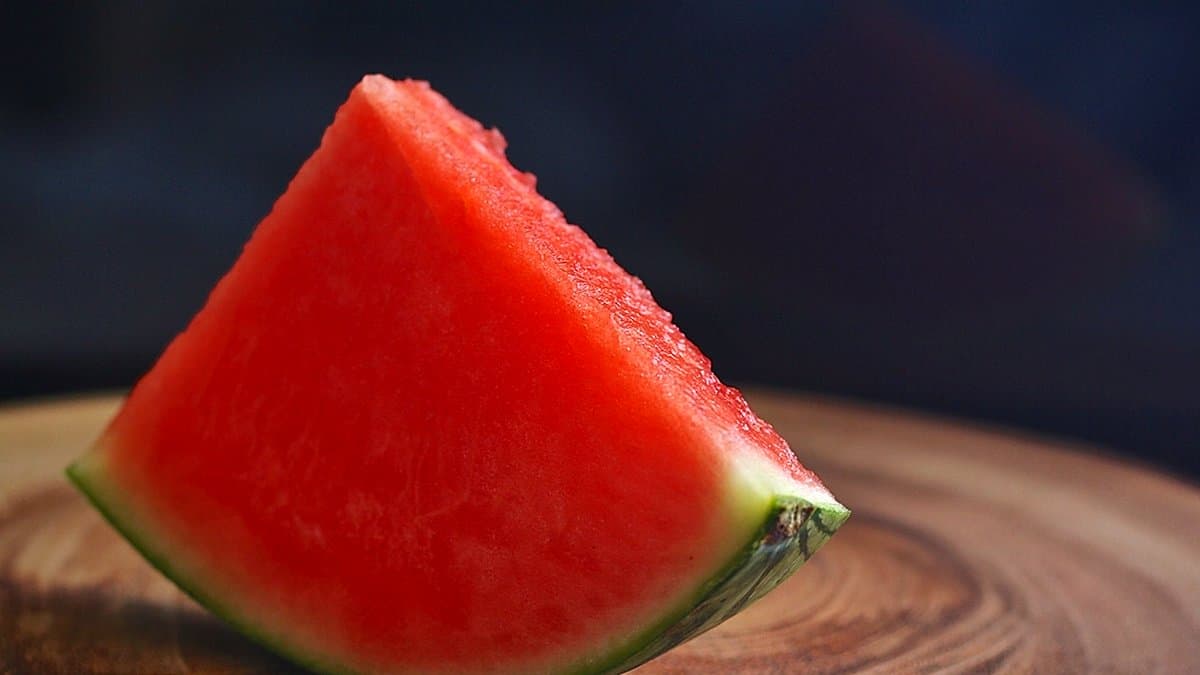 Cesta de verano con sandía fresca, gazpacho en botella, helados de colores y bebidas frías sobre mesa soleada