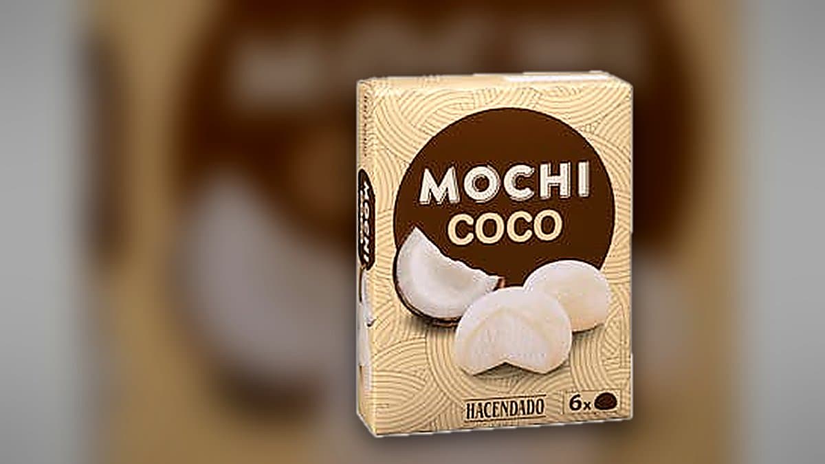 Bolas de helado mochi de coco con condensación en plato frío, caja de Hacendado al fondo, iluminación azul de congelador contrastando con tonos cálidos de verano