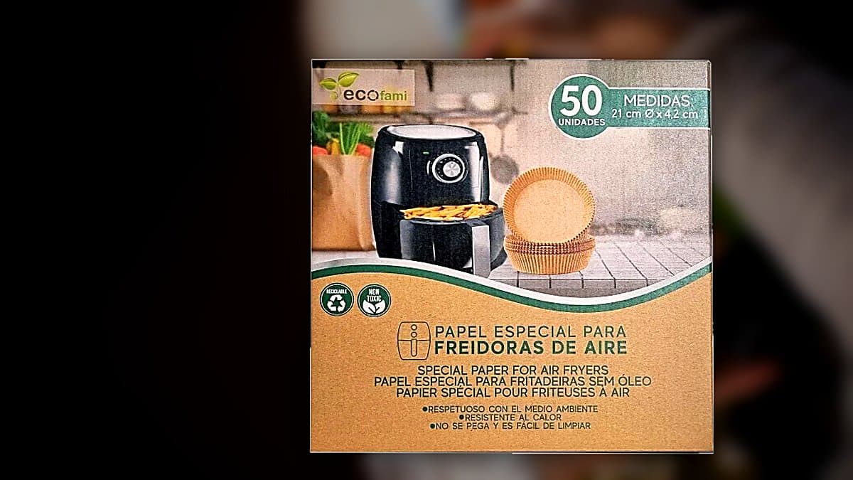 Papel molde desechable para freidora de aire junto a cesta de freidora en cocina moderna