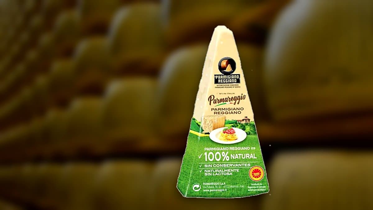 Wedge of Parmesan cheese with a grater and shavings on a rustic wooden board, Parmareggio package blurred in background, warm natural lighting