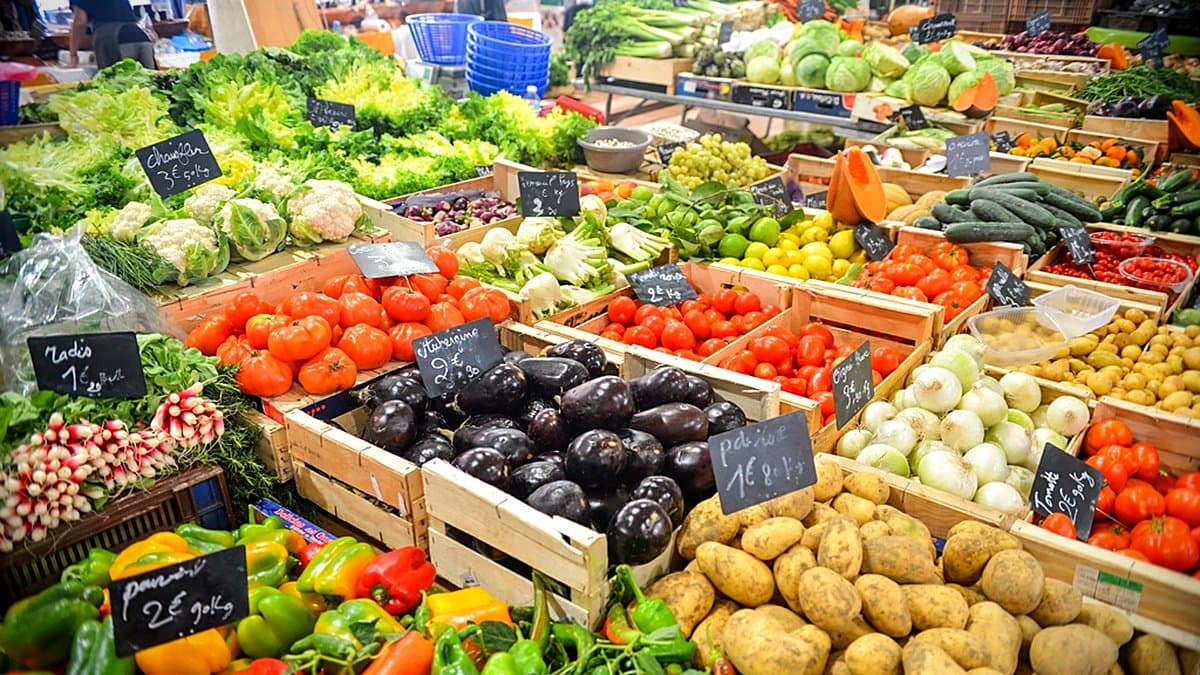 Frigorífico abierto con verdura congelada al lado de verdura fresca en mostrador de supermercado, contraste luz fría y cálida