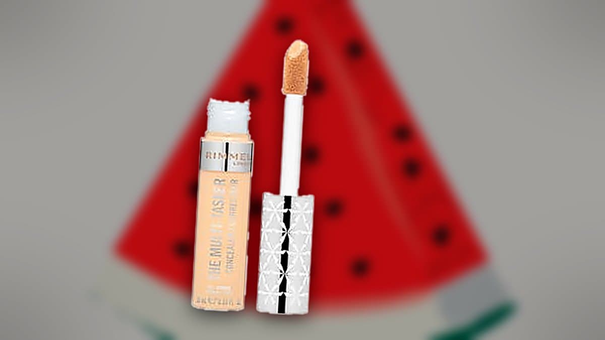 Tubo de multicorrector Rimmel London en tono Sand sobre vanidad con tonos cálidos, luz de verano, cosmética de belleza ordenada.