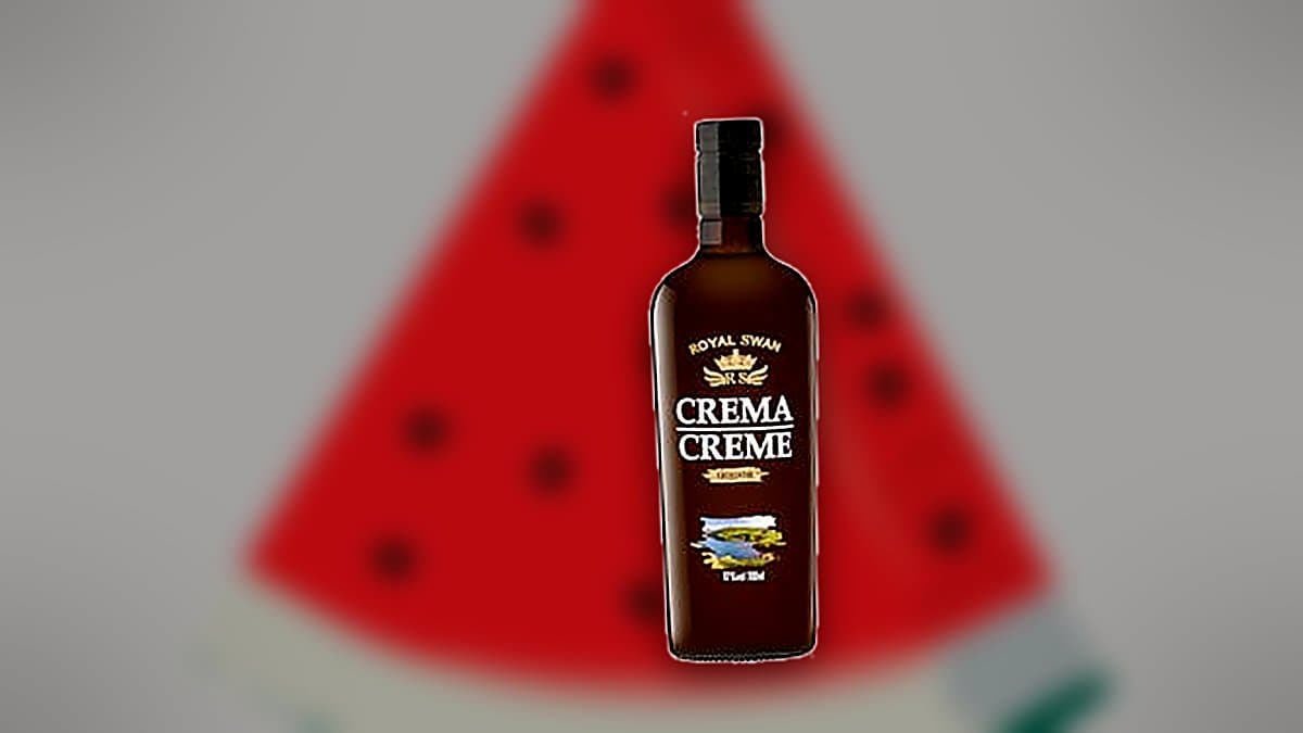 Botella de licor crema Royal Swan sobre barra de bar con copa de cristal llena de hielo, luz cálida reflejada en el vidrio