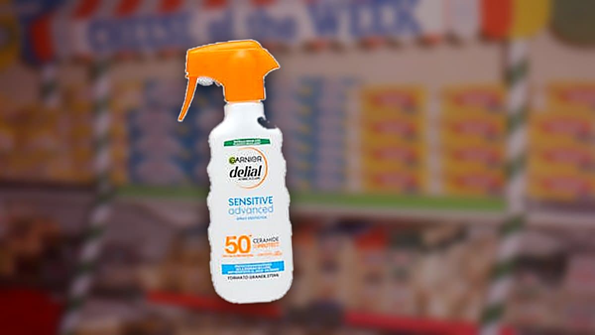 Dos botellas de protector solar Delial sobre toalla de playa con arena y luz de verano