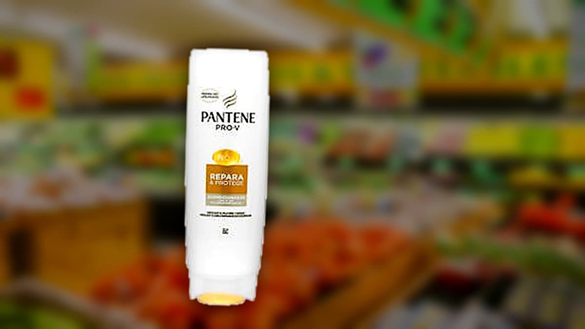 Bote de acondicionador Pantene Repara & Protege sobre encimera de baño mojada con gotitas de agua