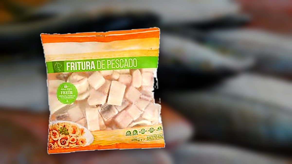 Plato de fritura de pescado ultracongelada con calamar, abadejo y langostino dorado recién salido del fuego, sobre mesa de chiringuito veraniego con limón