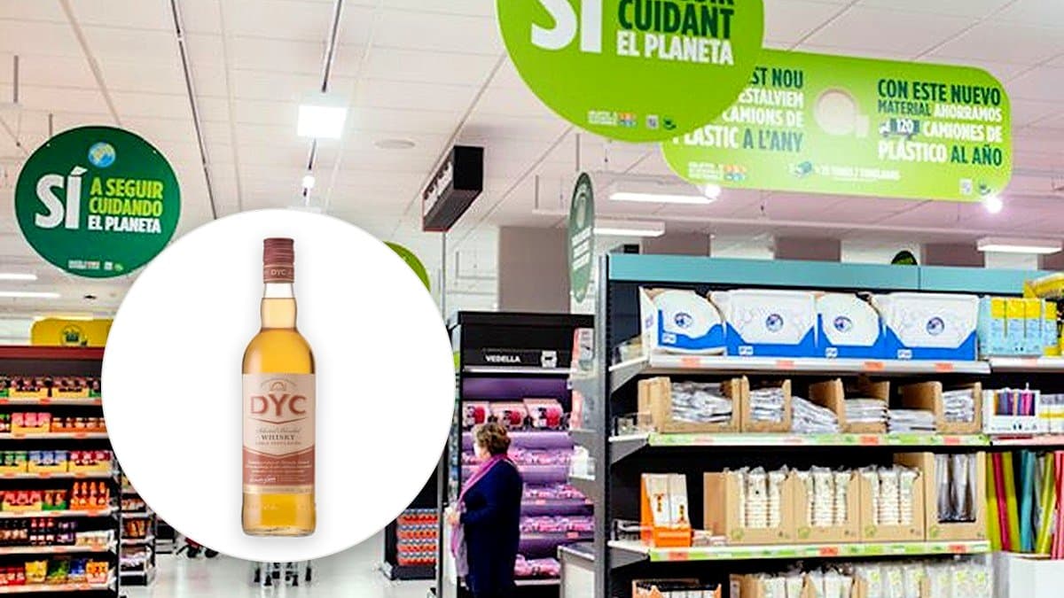Botella de whisky DYC de 70 centilitros sobre balda iluminada de supermercado, detalle de etiqueta y llenado ámbar