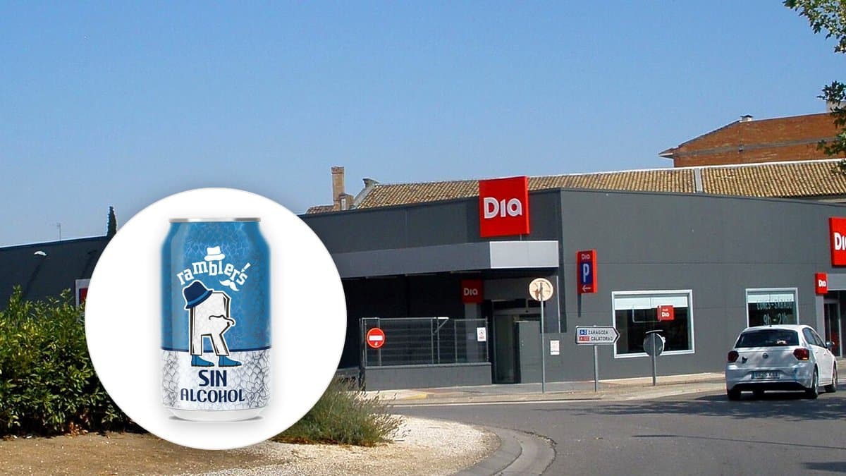 Botellines de cerveza sin alcohol de 33 cl alineados en una nevera de supermercado con condensación, luz de agosto entrando de fondo.