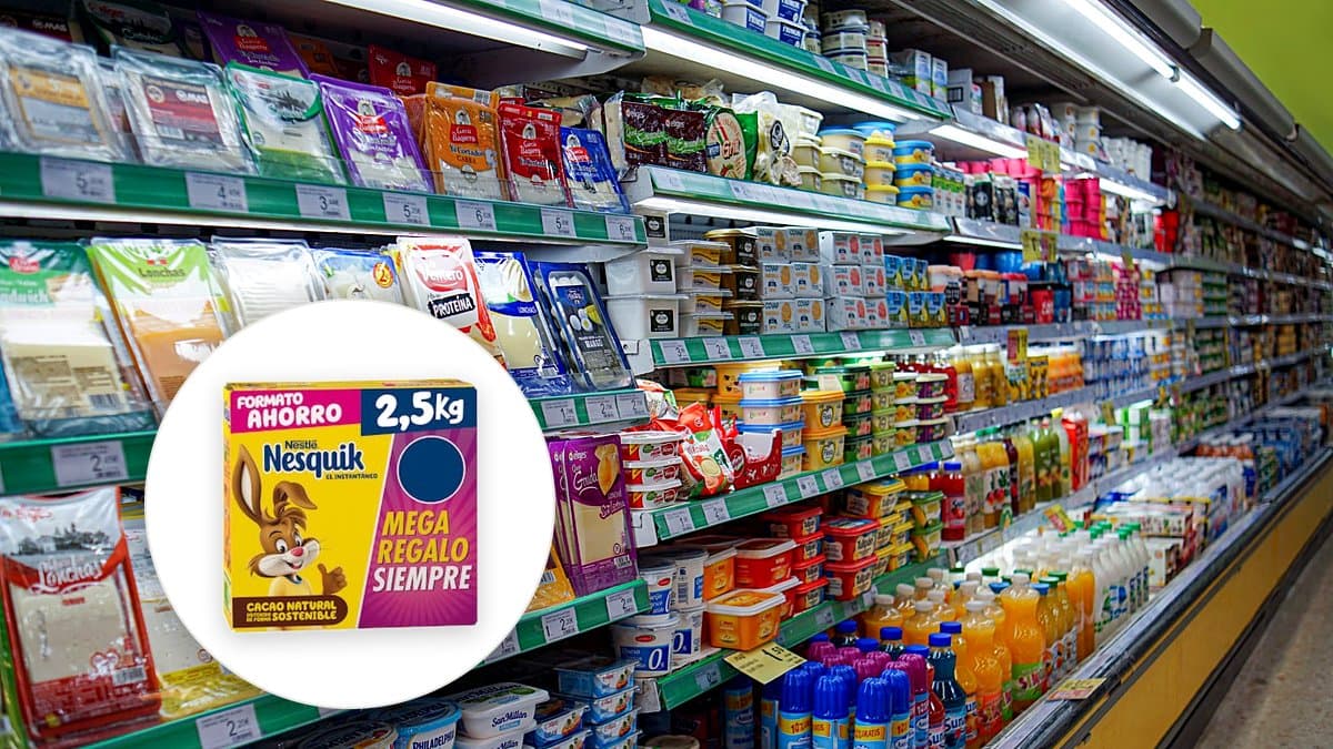 Bote grande de Nesquik cacao soluble en cocina española con taza de chocolate caliente y cucharilla, luz matinal suave