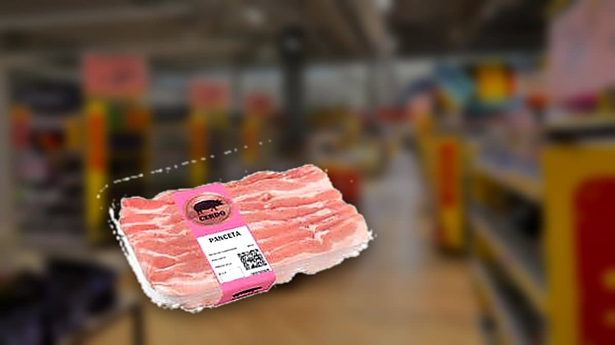 Bandeja de panceta de cerdo fresca en el mostrador de carnicería de Mercadona, iluminación fría de frigorífico, otras bandejas de carne desenfocadas al fondo