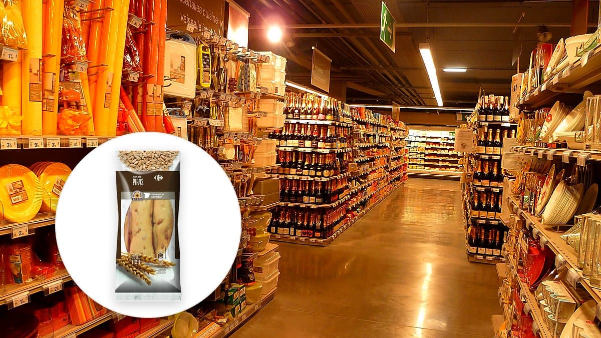 Pack de dos bolsas de palitos de pan con pipas de Carrefour sobre tabla de madera con aceitunas