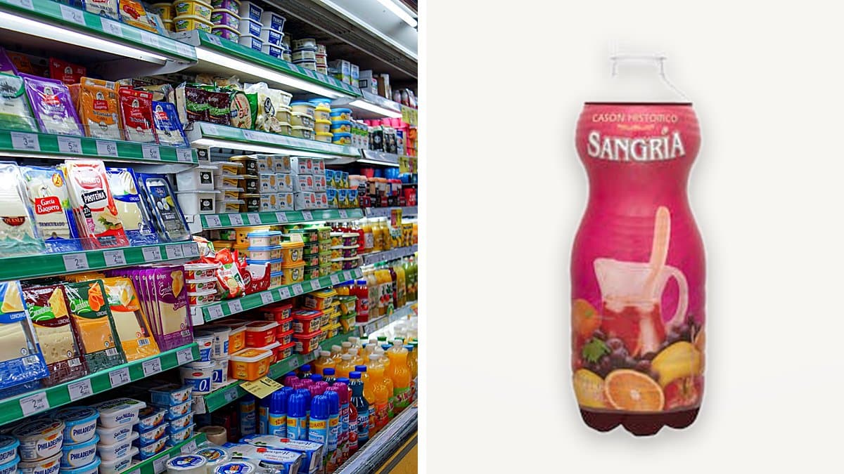 Carrito de la compra medio lleno con alimentos básicos en un pasillo de supermercado español, luz natural de otoño.