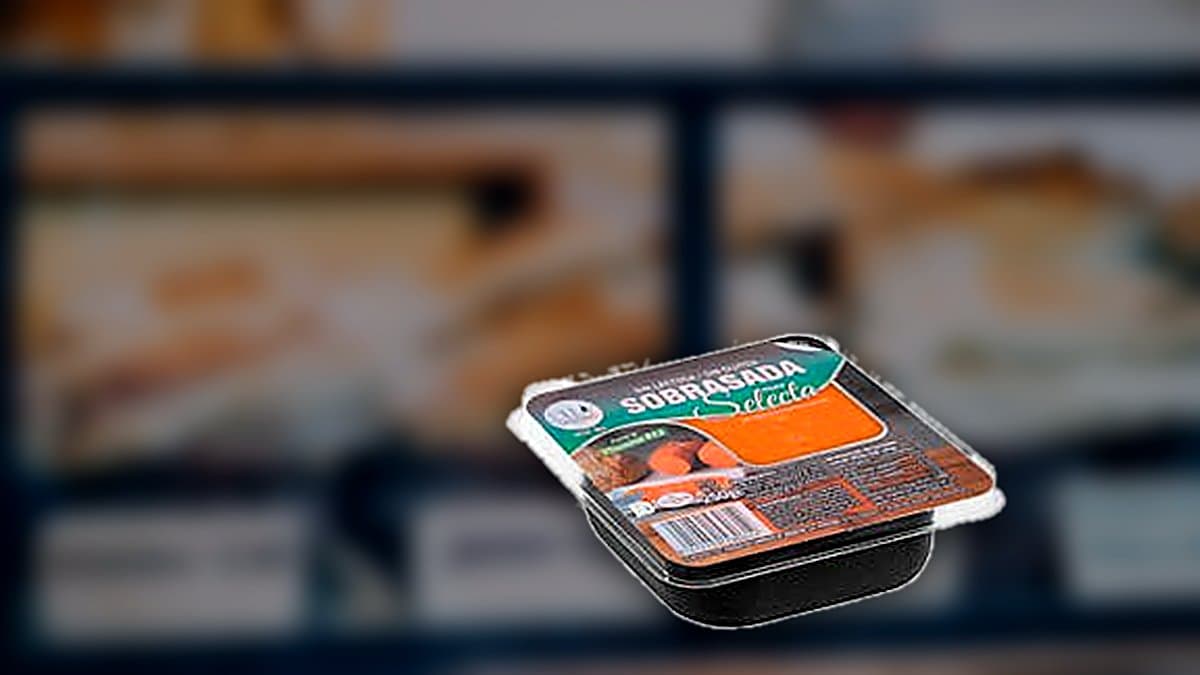 Rebanada de pan tostado cubierta con sobrasada roja en tabla de madera rústica