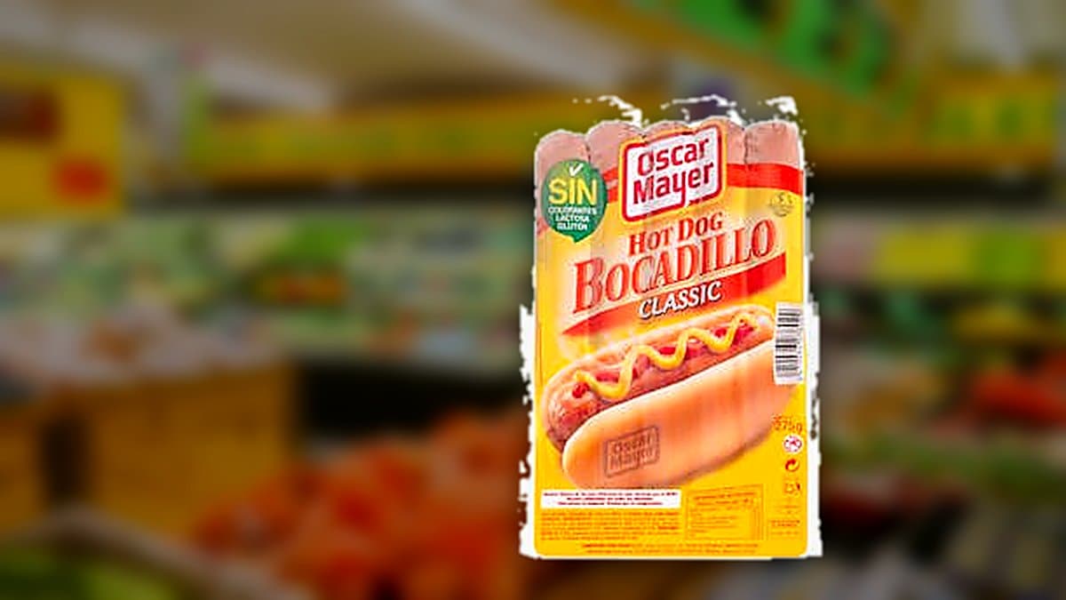 Paquete abierto de salchichas de bocadillo Oscar Mayer Classic junto a salchichas ahumadas sobre tabla de madera en cocina española, con fondo desenfocado de luz natural