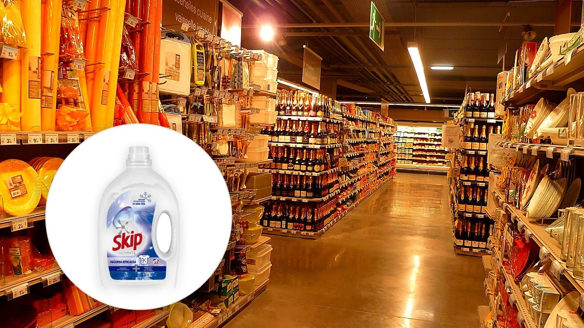 Botella grande de detergente líquido Skip Ultimate en estante sobre una lavadora frontal en cuarto de lavado español, con toallas dobladas y luz natural