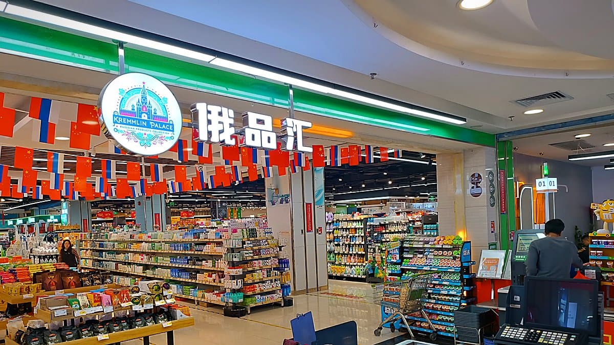 Fachada de vidrio del nuevo supermercado Action con clientes entrando, carros de compra, iluminación natural diurna, arquitectura moderna de tienda de descuentos.