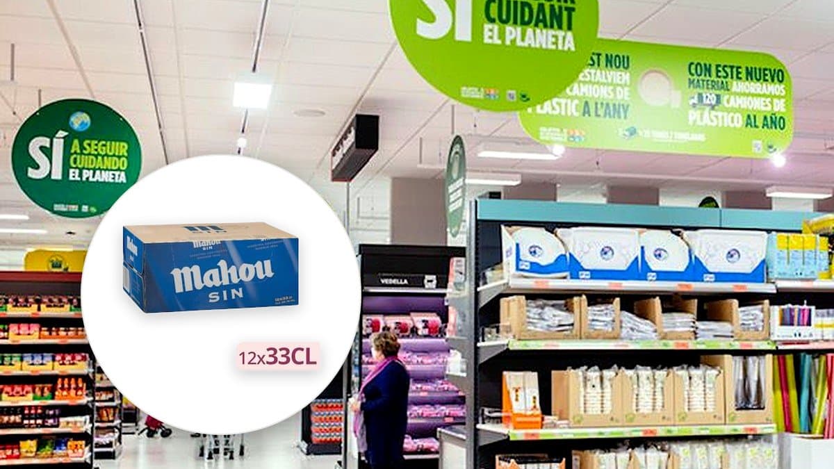 Pack de doce latas de cerveza Mahou sin alcohol en estantería de supermercado, condensación en aluminio, iluminación cálida de tienda minorista.