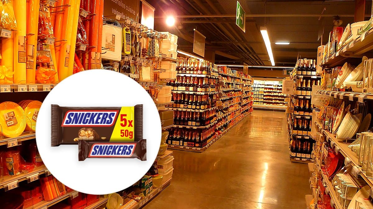 Pack de cinco Snickers abierto en mesa de madera junto a mochila escolar y hojas de otoño