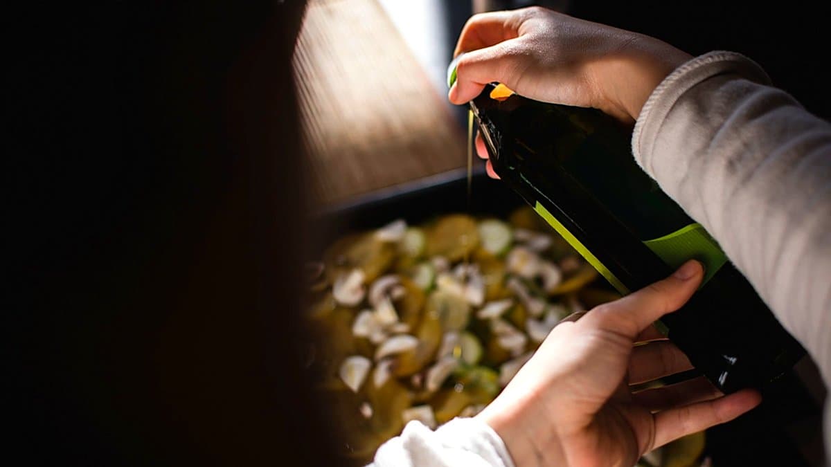 Estanterías de supermercado con aceite, arroz, pasta y productos básicos, mano de cliente seleccionando producto