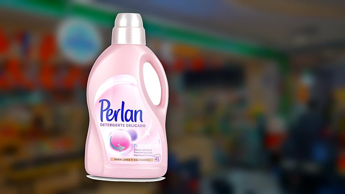 Jerséis de lana doblados junto a una garrafa de detergente Perlan para ropa delicada sobre un estante de lavandería.