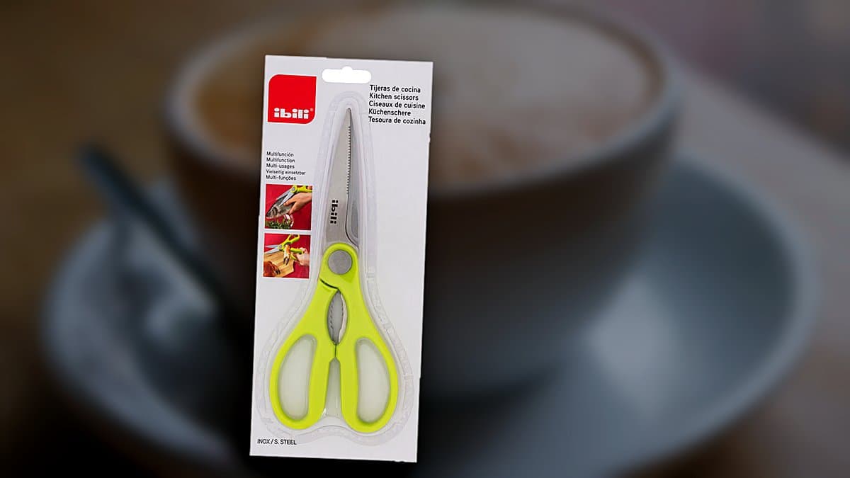 Tijera de cocina inoxidable de Ibili sobre tabla de madera con hierbas frescas y setas de otoño
