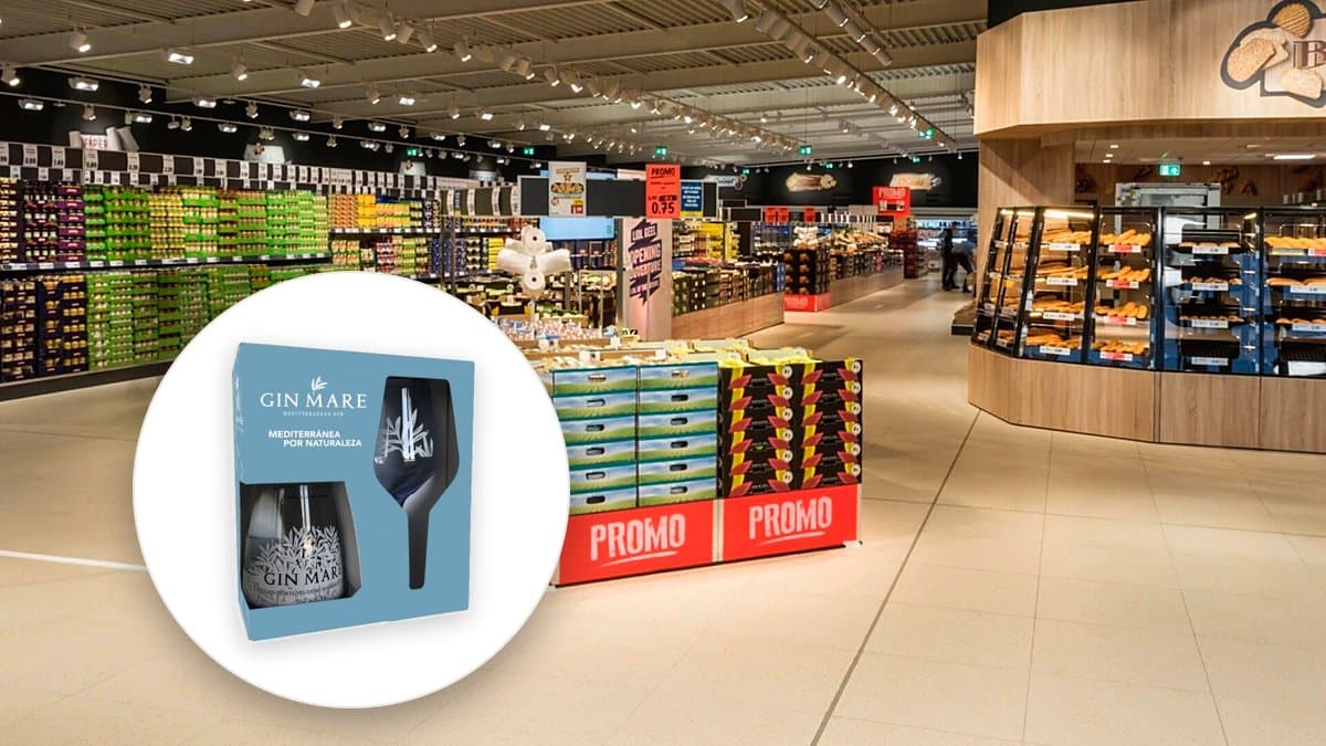 Persona leyendo un folleto de supermercado en la cocina junto a un móvil con ofertas y una lista de compra