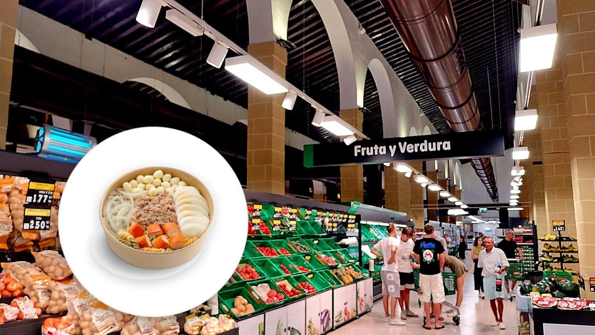 Bol de ensalada de pasta lista para comer con pasta, atún, surimi, huevo cocido y queso mozzarella en manos de una compradora en una estantería de refrigeración de supermercado.